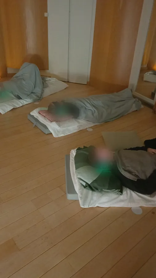 Deelnemers liggen onder dekens met koptelefoons op tijdens een ademsessie